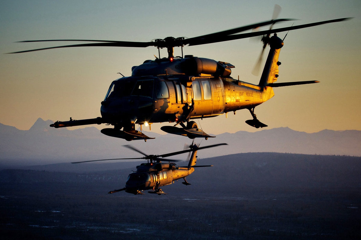 Two USAF Rescue HH-60 Pave Hawks flying in formation at sunset over Alaskan mountains